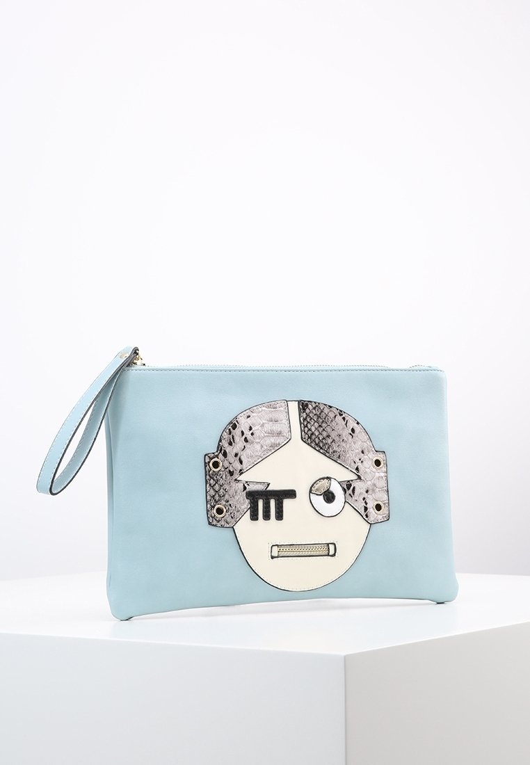 Pochette bracelet bleu clair avec un dessin de visage stylisé comprenant des zones texturées foncées, des yeux géométriques et une bouche zippée, posée sur un socle blanc.