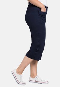Pantaloni corti blu navy fino al ginocchio realizzati in cotone misto, con tasche laterali, design aderente e dettaglio a bottoni all'orlo.