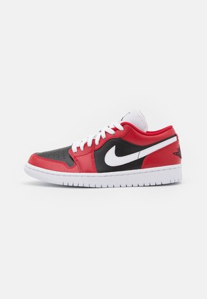 Zapatilla de corte bajo en rojo, negro y blanco con cordones blancos, puntera perforada y el logo blanco de Nike en el lateral.