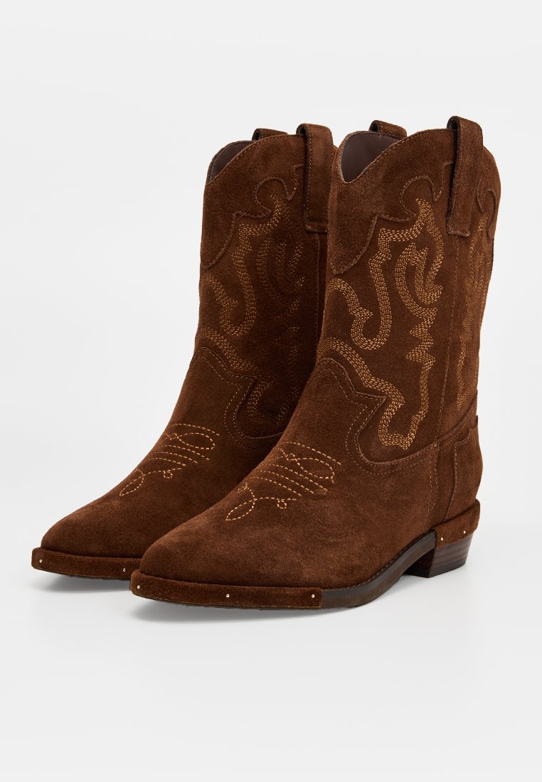 Braune Wildleder-Cowboy-Stiefel mit dekorativen gelben Nähten, spitzen Zehen und einem niedrigen, gestapelten Absatz. Mit westlich inspirierten Stickereien verziert.