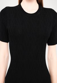 Black knitted short-sleeve top featuring a textured geometric pattern, a ribbed crew neckline, and a form-fitting silhouette.