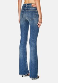 Rozšířené tmavě modré džíny z denimu s vysokým pasem, jemným vyblednutím a označením na zadním pásu. Klasický design s pěti kapsami.