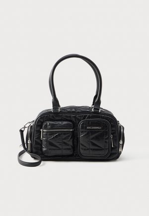 Černá prošívaná kabelka vyrobená z umělého materiálu, s dvěma předními zipovými kapsami a odnímatelným ramenním popruhem. Hladký povrch, zaoblený tvar.