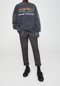 Sudadera gris de gran tamaño con el gráfico "PINK FLOYD" y el logo del triángulo de arcoíris, combinada con pantalones cortos gris oscuro y zapatillas negras.