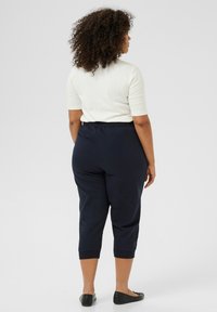 Pantaloni jogger cropped navy con cintura elastica, abbinati a un top in maglia bianco. Presentano una vestibilità morbida e orli a maniche. Ballerine nere.