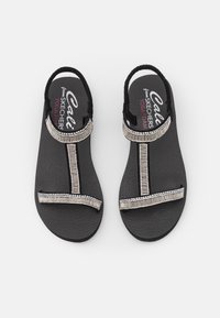 Sorte sandaler med en teksturert såle, med perlede detaljer langs stroppene og en yogaskum fotbed for komfort.