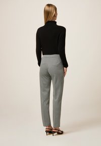 Zwarte coltrui, slim fit ontwerp. Grijs en zwart geblokte broek, taps toelopende pasvorm, zijzakken en enkellange zoom.