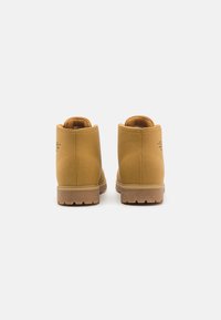 Stivaletti alla caviglia in suede giallo con finitura testurizzata, suola in gomma e collare imbottito. Presentano un marchio sul retro e un design semplice.