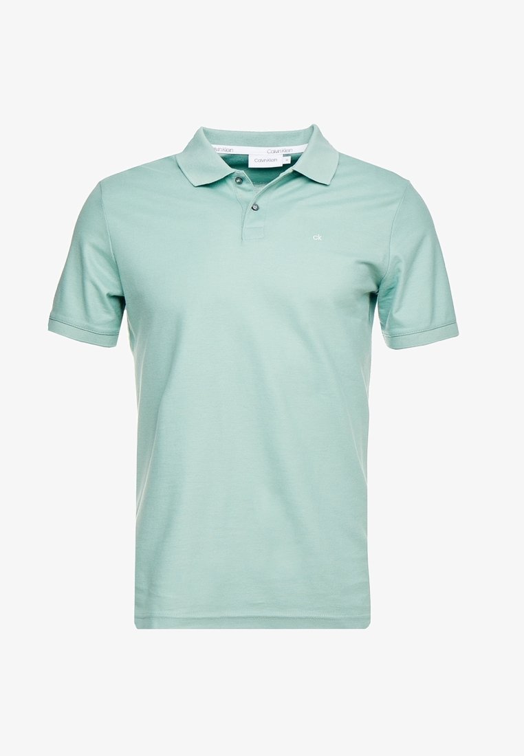Polo vert clair en coton doux, avec un col classique, des manches courtes, une patte à deux boutons et un logo discret sur la poitrine.