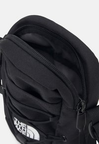 Zaino nero con tessuto testurizzato, scomparto principale con cerniera, tasche frontali e logo The North Face, che mostra un design resistente e pratico.