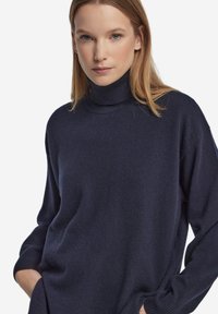 Mörkblå polotröja i mjukt stickat material med avslappnad passform och ribbade muddar. Minimalistisk design utan synliga mönster.