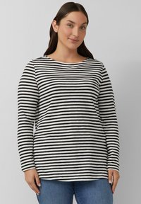 Zwart-wit gestreepte longsleeve met een ronde hals, gemaakt van zachte stof, gecombineerd met blauwe jeans. Eenvoudig, casual ontwerp.