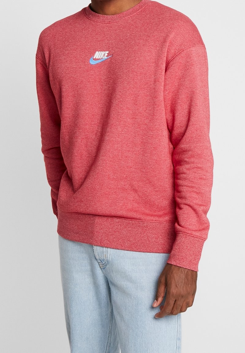 Rotes Sweatshirt mit Rundhalsausschnitt aus weichem Stoff und geripptem Saum, mit kleinem weißen und hellblauen Nike-Logo auf der Brust.