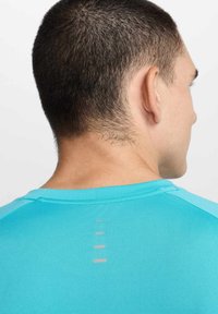 T-shirt atlético turquesa com uma textura suave e riscas verticais refletivas nas costas. Design justo, decote redondo.