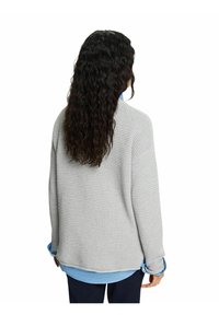 Grijze textuur trui met een relaxed fit, met een wafelbreipatroon en een ronde zoom, gelaagd over een lichtblauwe shirt.