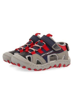 Sandalias de exterior con parte superior sintética gris, correas azul marino, acentos rojos y suelas texturizadas. Cuentan con cierres ajustables y un diseño de punta abierta.