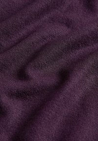 Ljubičasta tkanina s teksturom, sa mekim, finim pletenim uzorkom, koja sadrži suptilne varijacije u nijansama i glatku površinu.