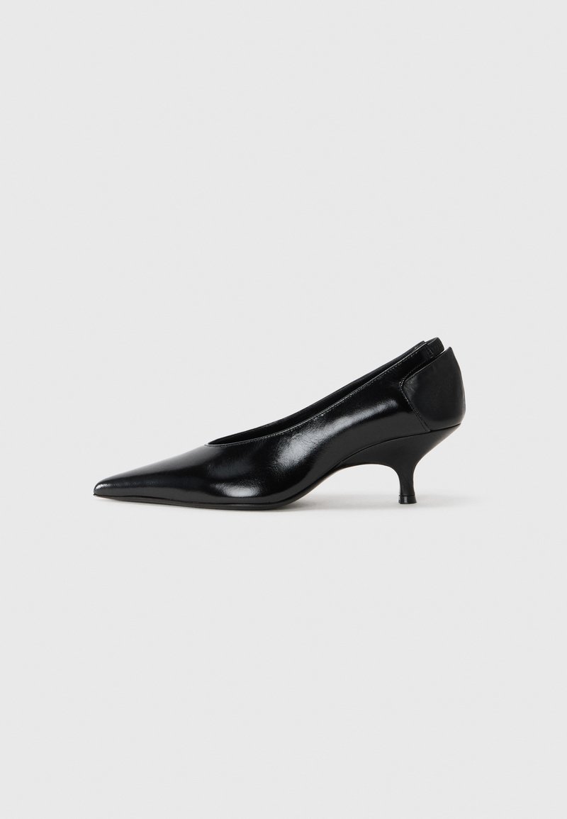 Svart läderpumps med spetsig tå, låg klack, elegant design och slät yta. Har en slip-on-stil utan synlig hårdvara.