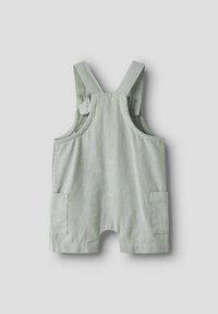 Mono de algodón verde claro con tirantes ajustables, dos bolsillos laterales y un corte relajado. Presenta un acabado de tejido texturizado.