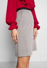 Hame harmaa kuviollinen, leveähelmainen, jossa on musta vyötärö. Yhdistetty punaisen paidan kanssa, jossa on röyhelöhihoja.