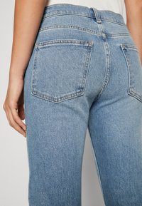 Bleka blå denimjeans med hög midja, med två bakfickor och rak benform. Synlig sömnadsdetalj.