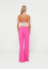 Halter-neck crop top in light lavender and wide-leg pants in vibrant pink; soft fabric with a smooth texture and relaxed fit.