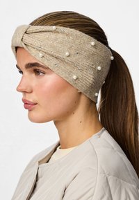 Bežīgs adīts matu josla ar pītas dizainu, rotāta ar baltām pērlem un sudraba akcentiem. Gluda tekstūra papildina ikdienas apģērbu.