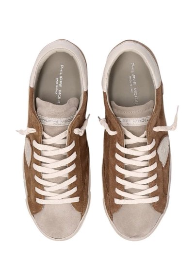 Sneakers in suede marrone con dettagli in pelle bianca, caratterizzati da punta rotonda, lacci bianchi e soletti con logo. Design classico a bassa top.