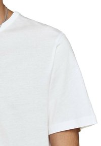 T-shirt bianco in cotone con colletto rotondo e maniche corte, caratterizzato da una texture morbida e liscia e bordi rifiniti con cura.