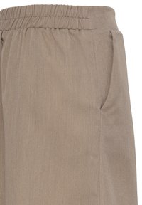 Primer plano de pantalones con cinturilla elástica beige con bolsillo lateral, mostrando la textura de la tela y los detalles de costura.