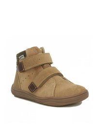 Stivale alla caviglia in suede marrone con due cinturini in velcro, suola in gomma e dettagli della cucitura. Perforazioni sui lati per traspirabilità.