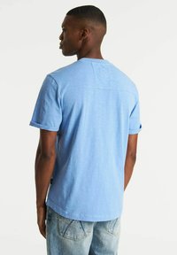 T-shirt azzurro chiaro a maniche corte con colletto rotondo, taglio casual e dettaglio della cucitura orizzontale sul retro, realizzato in tessuto morbido e traspirante.