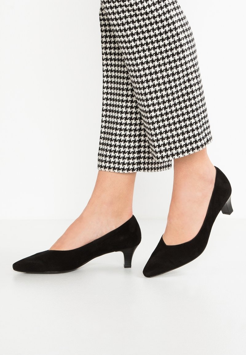 Escarpins bas en suede noir avec un design à bout pointu. Caractérisés par une texture subtile et un talon modeste et confortable. Assortis à un pantalon à motif à carreaux.