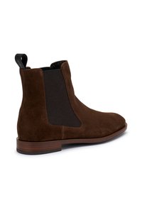 Stivale alla caviglia in suede marrone con pannelli elastici laterali, una linguetta per il tallone e suola in legno piatta, caratterizzato da una silhouette elegante e texture liscia.