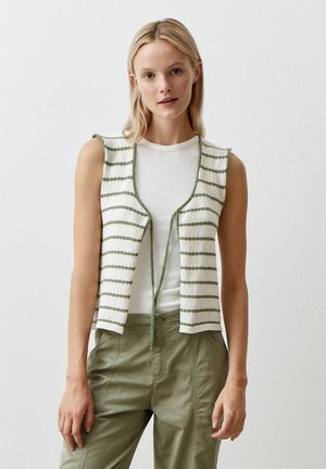 Gebreide vest met verticale groene strepen op een witte achtergrond, open voorkant ontwerp en een striksluiting, gedragen over een wit T-shirt.