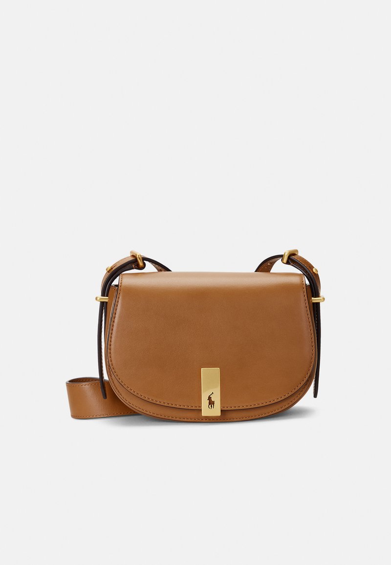 Brūna ādas crossbody soma ar izliekta vāka daļu, zelta aksesuāriem un redzamu logotipa akcentu. Iespējamas regulējamas siksnas un gluda tekstūra.