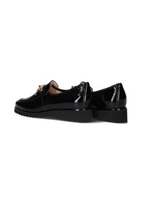Zwarte lakleren schoenen met een lage wedgehak, voorzien van een minimalistisch ontwerp en een decoratieve hardwareaccent aan de voorkant.