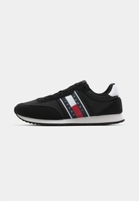 Zwarte sport schoenen met een gladde textielen bovenkant, voorzien van witte, rode en blauwe horizontale strepen. Rubberen zool met een gestructureerd profiel.