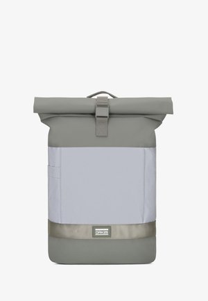 Šedý ruksak so zrolovaným vrchom s hladkým plastovým povrchom, obsahujúci predné vrecko, nastaviteľný popruh a štvorcový tvar. Na prednej strane je výrazné logo značky.