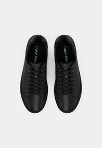 Ζευγάρι μαύρα sneakers Calvin Klein με κορδόνια, σε θέα από πάνω πάνω σε απλό λευκό φόντο.