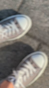 Világosszürke és fehér vászon sportcipők, amelyek körte hogy együtt játszanak, fehér fűzőkkel és kontrasztos panelek. A talp gumiból készült, texturált mintázattal.