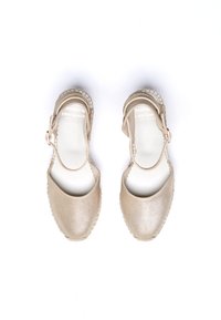Espadrilles métalliques dorées avec un bout arrondi, une bride de cheville et des semelles en jute tressé. Texture lisse et design minimaliste.