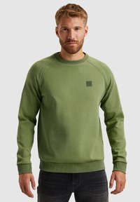 Groene sweatshirt met lange mouwen, ronde halslijn, textuur en gestikte details. Kleine labelaccent op de borst.