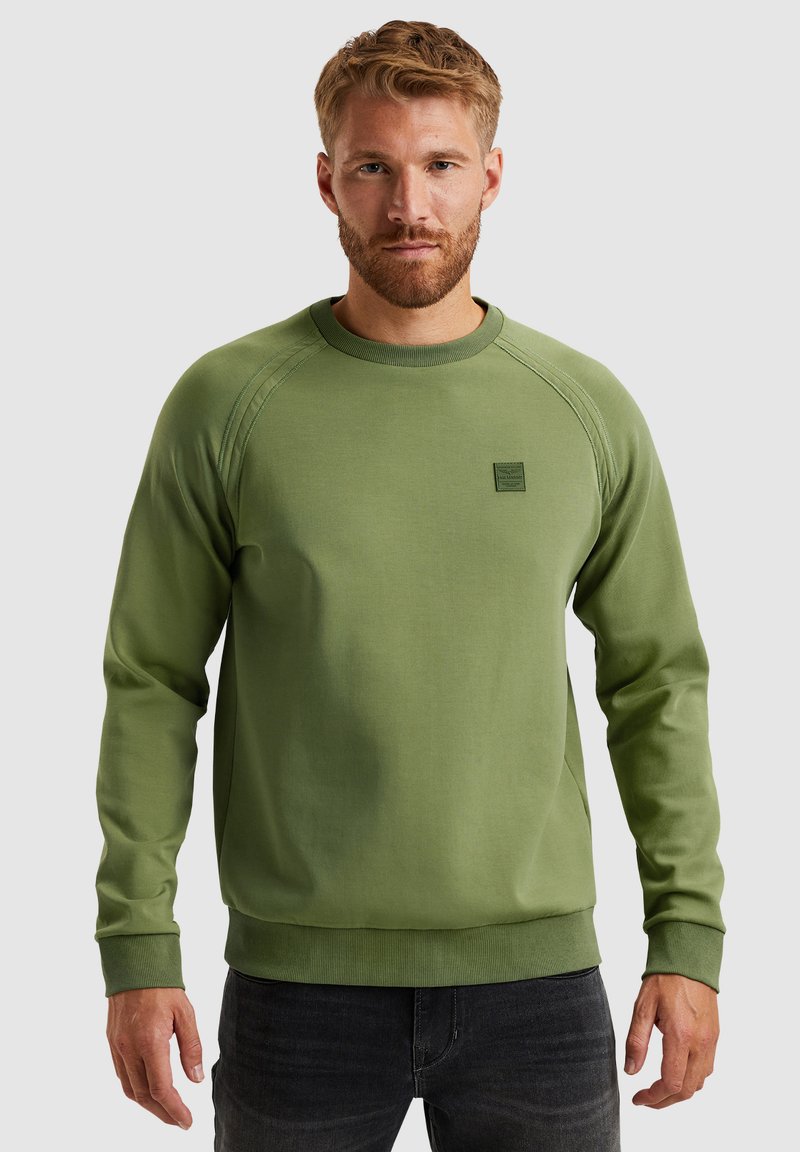 Groene sweatshirt met lange mouwen, ronde halslijn, textuur en gestikte details. Kleine labelaccent op de borst.