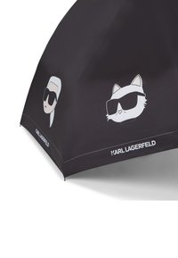 Black folding umbrella featuring cartoon graphics of a person and a cat in sunglasses. It includes the "Karl Lagerfeld" logo along the edge.