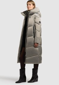 Langer, leichter grauer Steppmantel mit hohem Kragen und Reißverschlusstaschen, mit einer glatten, schlichten Textur und einem geometrischen Steppmuster.