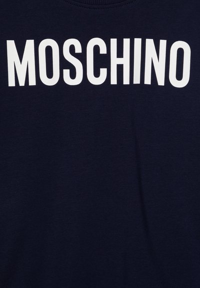 Mornarska majica s velikim bijelim logom "MOSCHINO" na prednjoj strani. Izrađena je od mekog pamuka, s dizajnom okruglog izreza i kratkim rukavima.