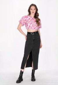Blomstret cropped top med puffærmer i pink og lilla nuancer, parret med en sort denim nederdel med slids foran og sort bælte, båret med sorte støvler.