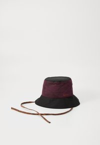 Chapeau seau bicolore avec un dessus bordeaux et un bord noir, fabriqué en tissu durable avec une finition texturée et une sangle marron à motifs.