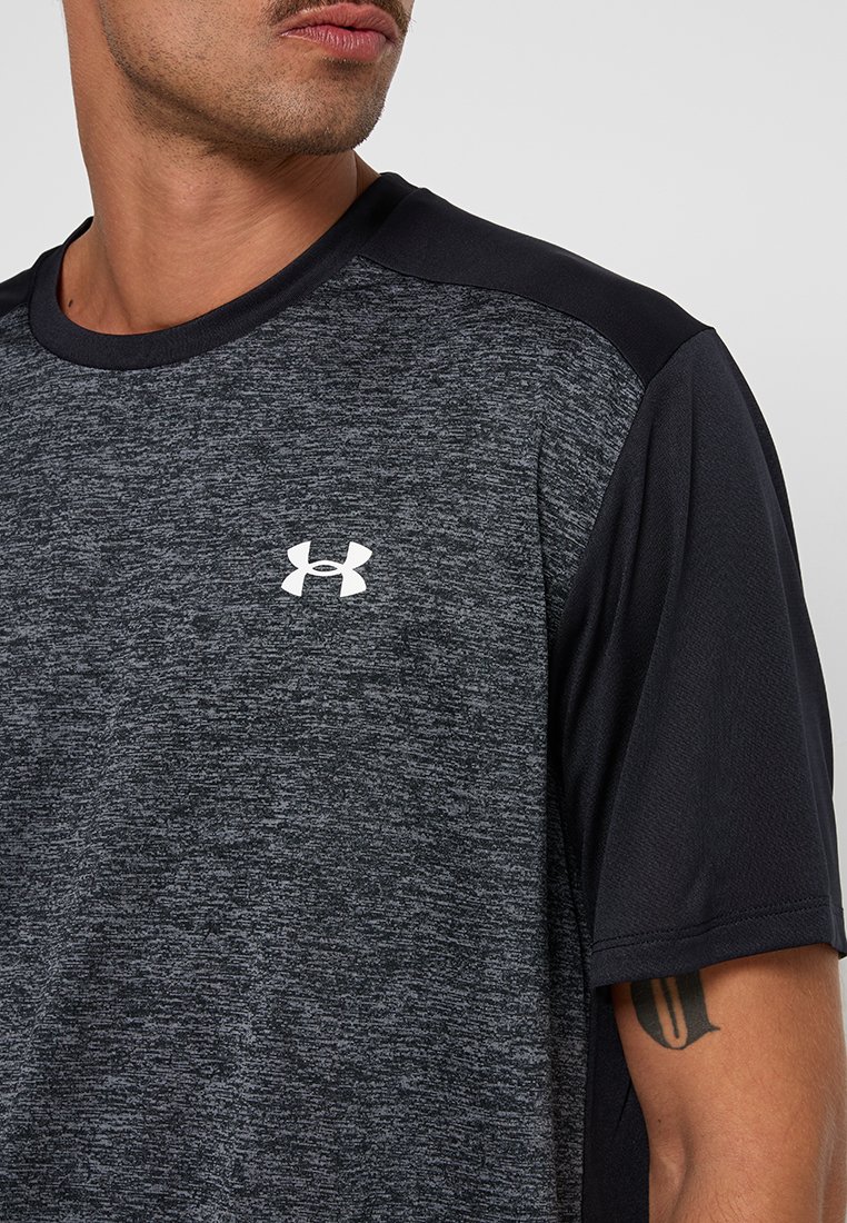 T-shirt de sport noir et gris avec un tissu texturé, des manches courtes et un petit logo blanc sur la poitrine.